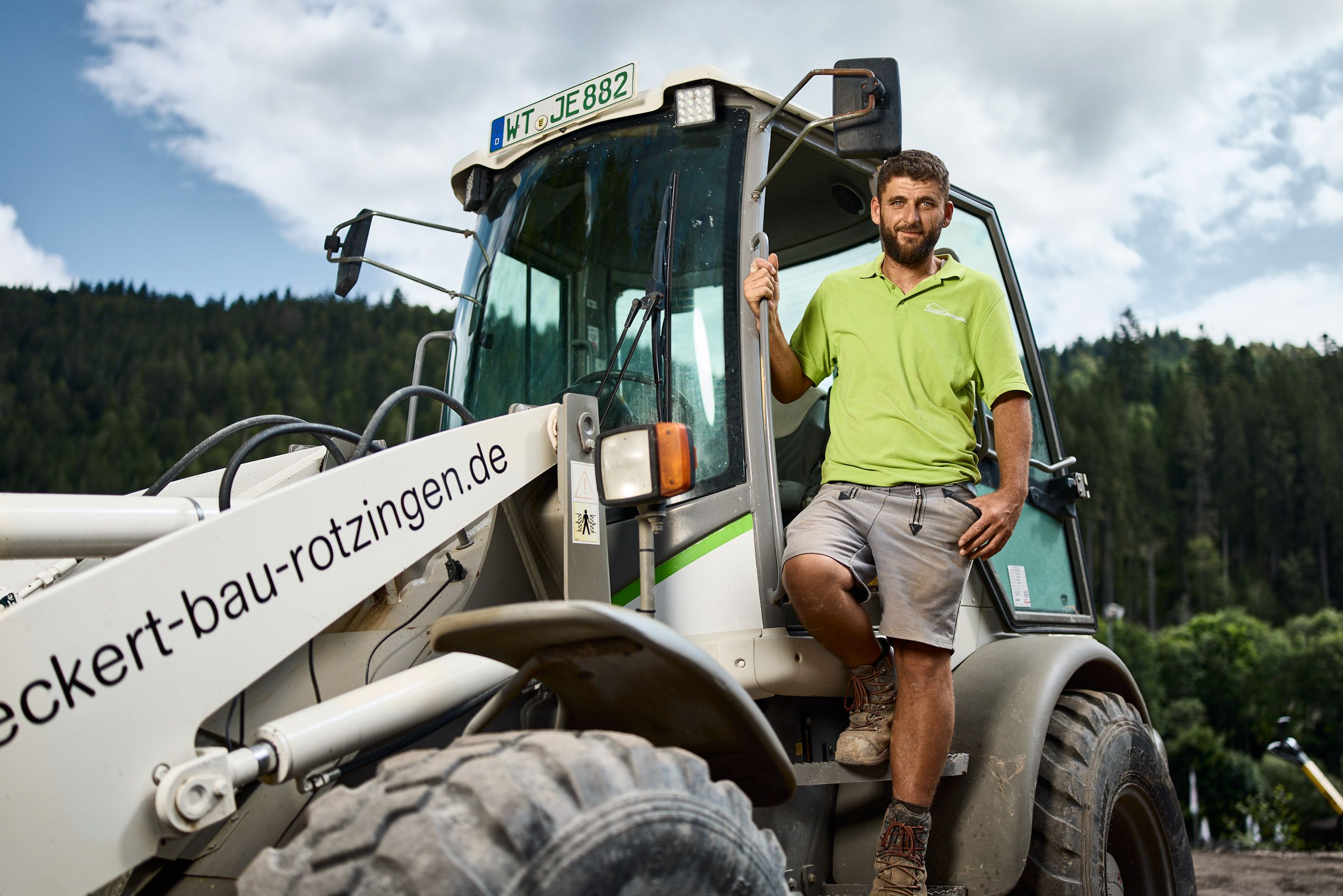 Mitarbeiter Hamez Bytyqi neben einem Baustellenfahrzeug auf einer Baustelle