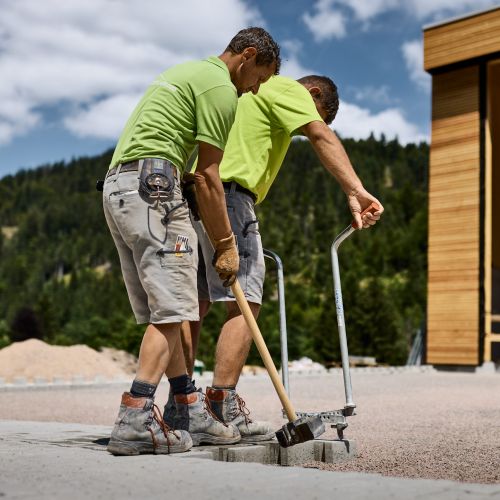 Zwei Mitarbeiter der Firma Eckert verlegen Pflastersteine auf einer Baustelle