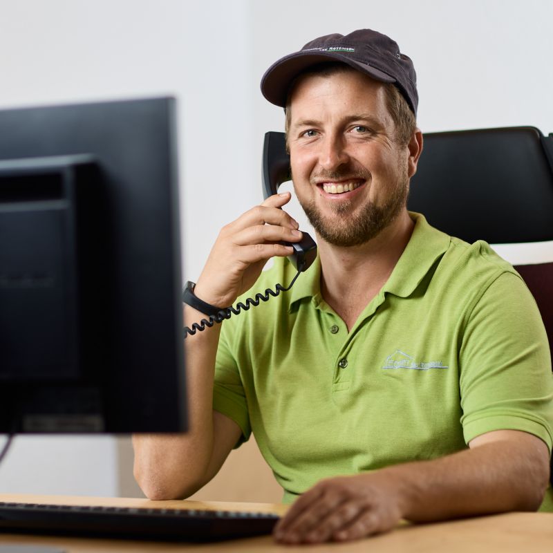 Jürgen Eckert an einem Schreibtischplatz mit einem Telefonhörer am Ohr